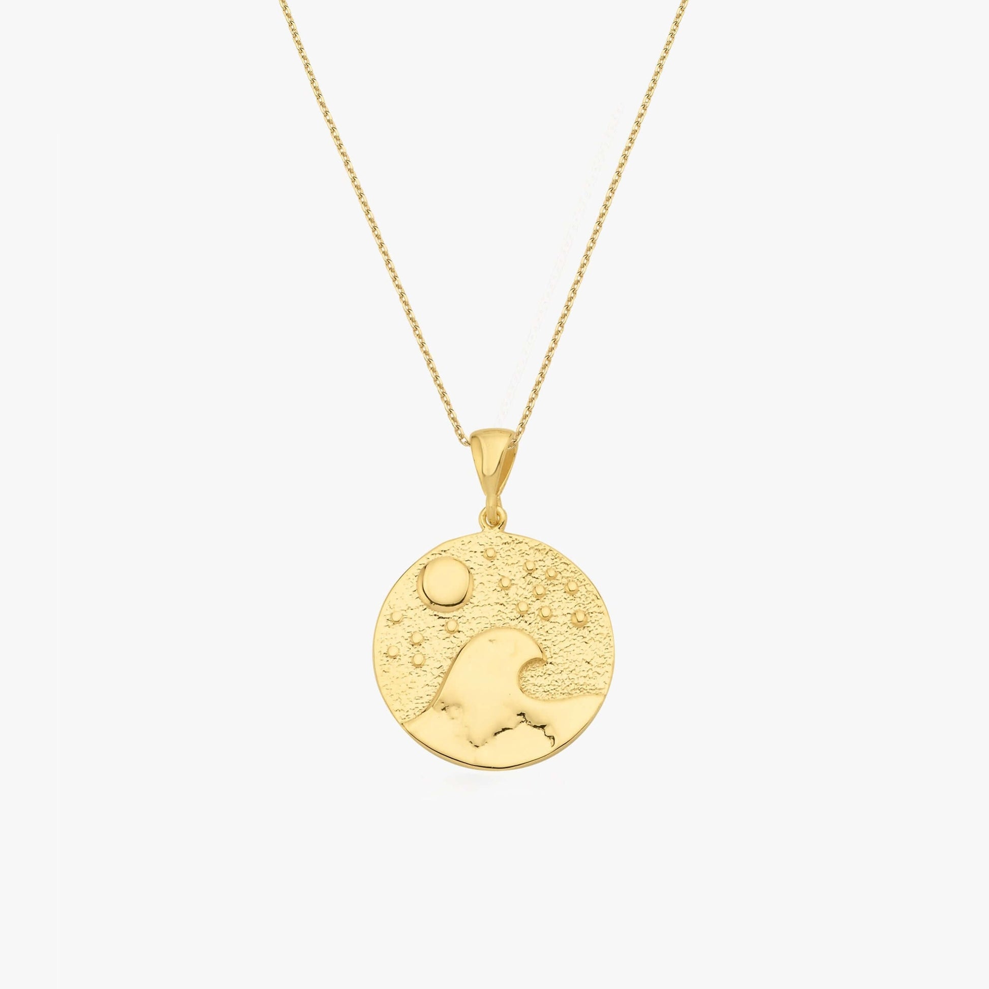 Gold pendant necklace featuring a wave and sun design on a textured circular charm. Elegant jewelry piece.