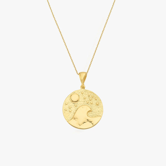 Gold pendant necklace featuring a wave and sun design on a textured circular charm. Elegant jewelry piece.