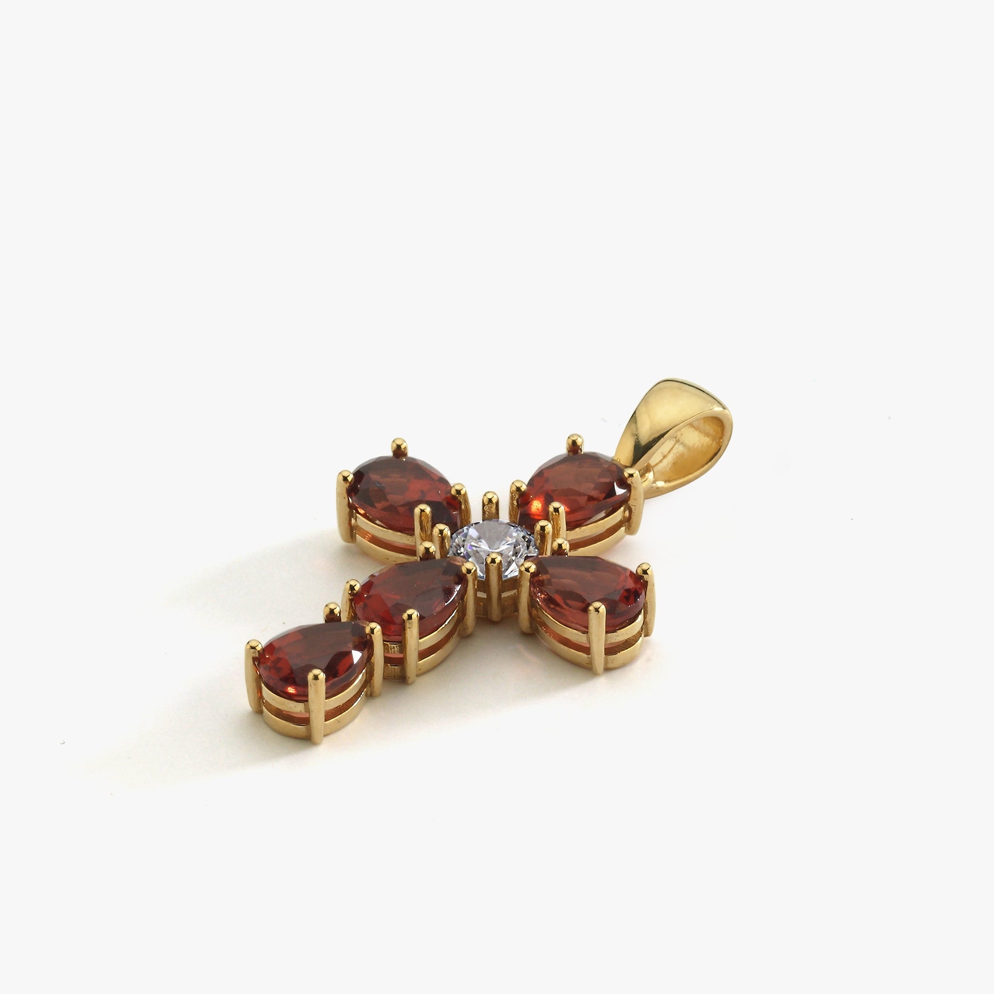 Gold cross pendant with red gemstones and central white diamond on white background. Elegant jewelry design.