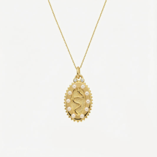 Gold necklace with a pendant featuring a face design on a white background