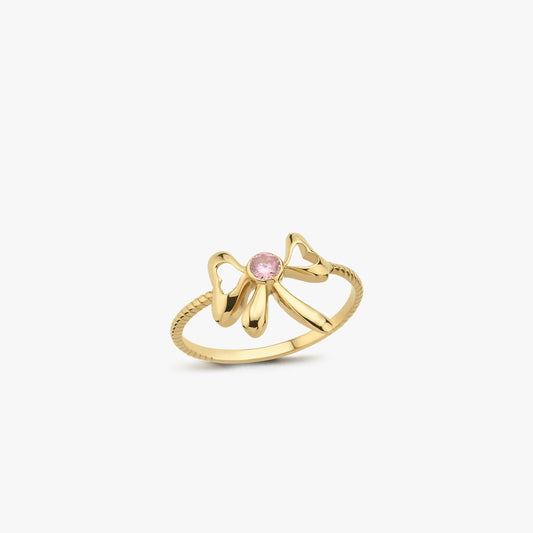 The Mionza Bow Ring in 14K Solid Gold showcases a delicate bow design adorned with a pink gemstone set at its center. The band's textured pattern enhances the overall elegance of this knot love ring, all highlighted against a plain white background to emphasize the intricate details.