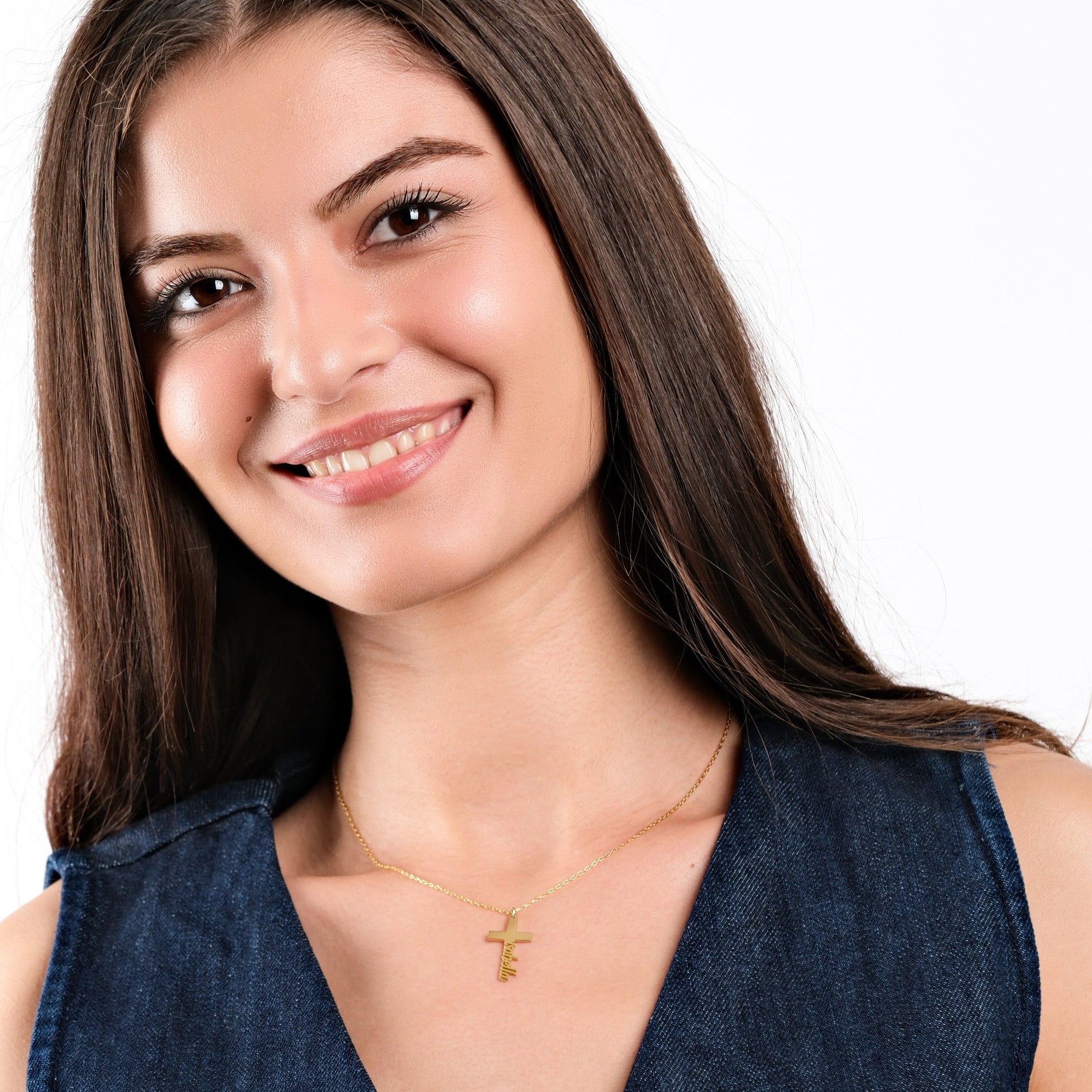 Smiling woman wearing gold initial necklace with denim top, showcasing stylish fashion accessory.