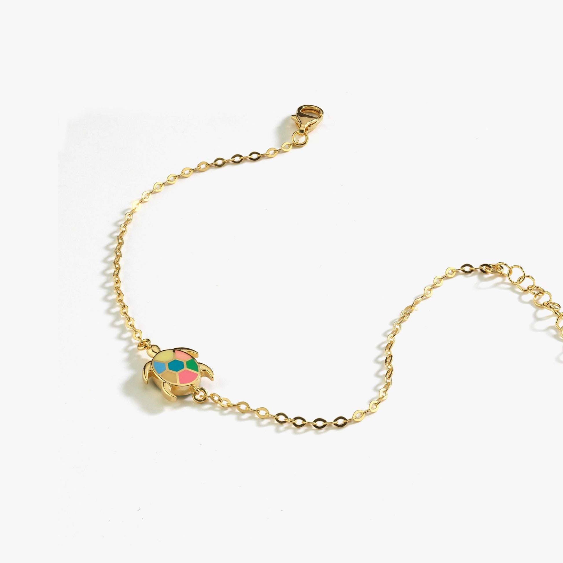 Gold chain bracelet with colorful turtle charm on white background, perfect for ocean-inspired fashion accessories.