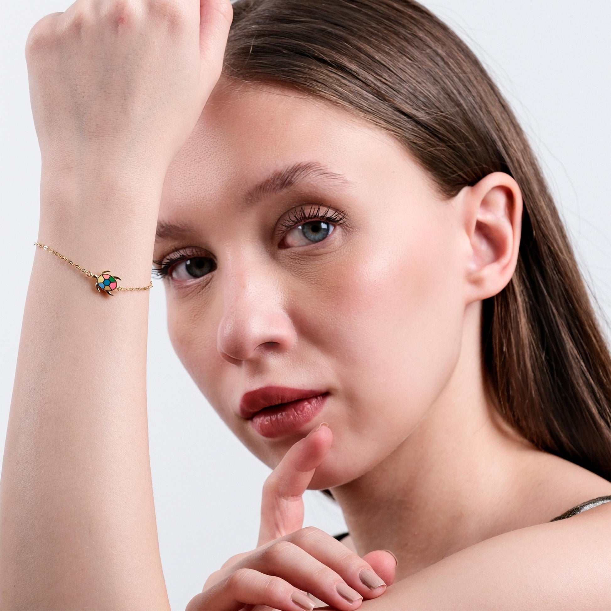 Woman posing with colorful turtle bracelet, displaying elegant jewelry fashion and natural beauty.
