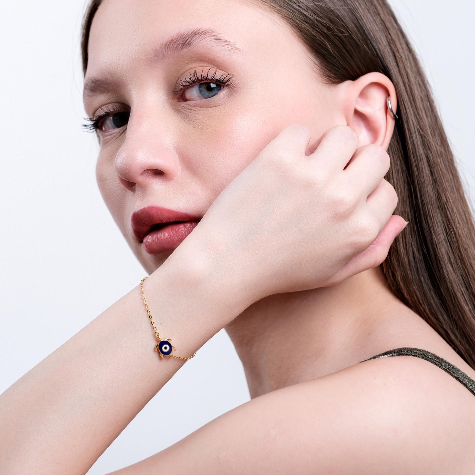 Woman with elegant evil eye bracelet, close-up portrait, showcasing minimalist jewelry and subtle makeup.