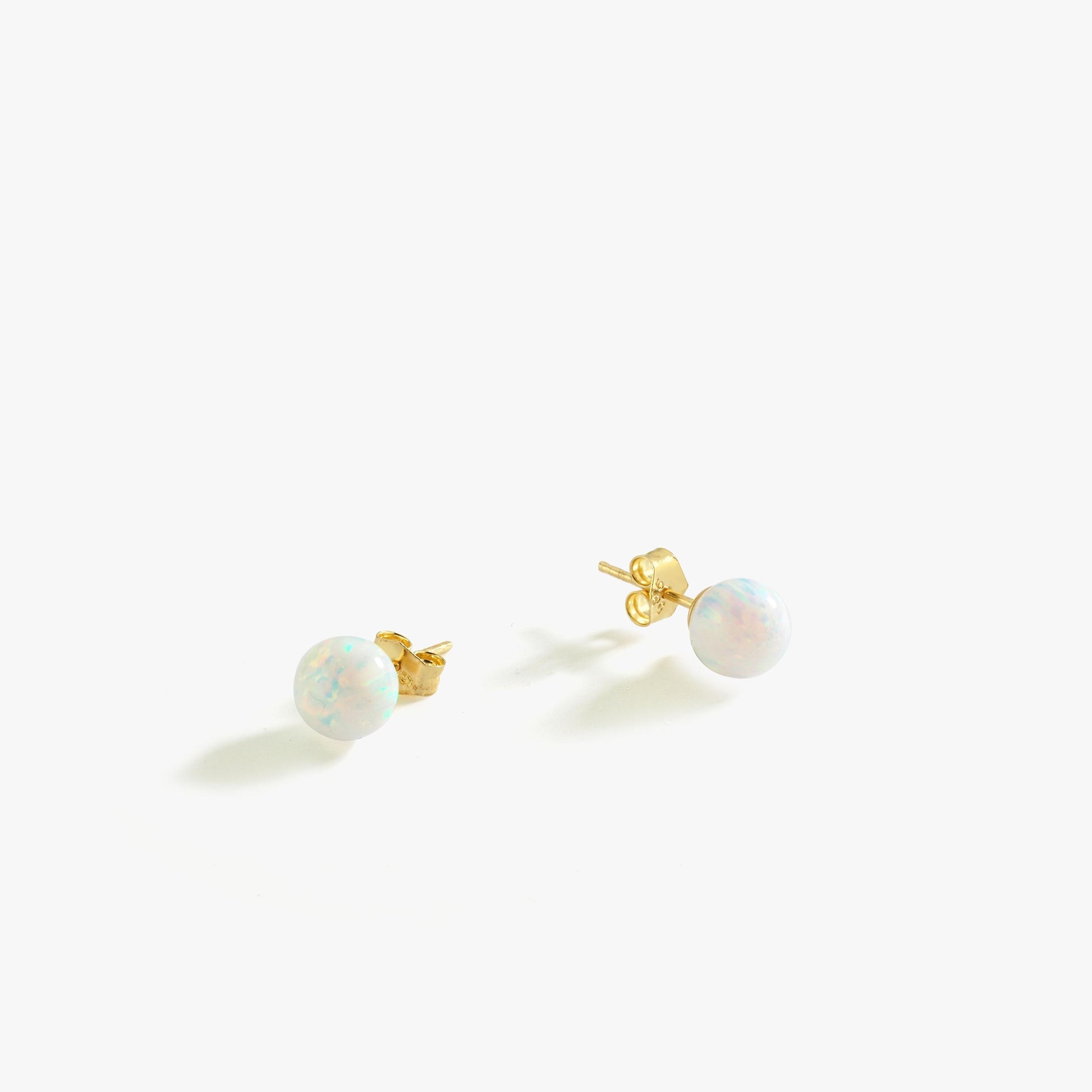 A pair of 14K gold opal stud earrings displayed against a white background, highlighting their delicate shimmer.