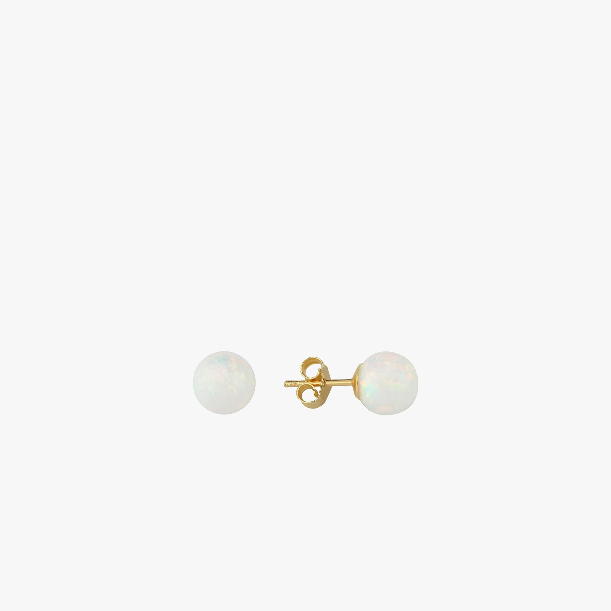 A minimal and elegant flat-lay of 14K gold opal stud earrings, emphasizing their soft, luminescent tones.