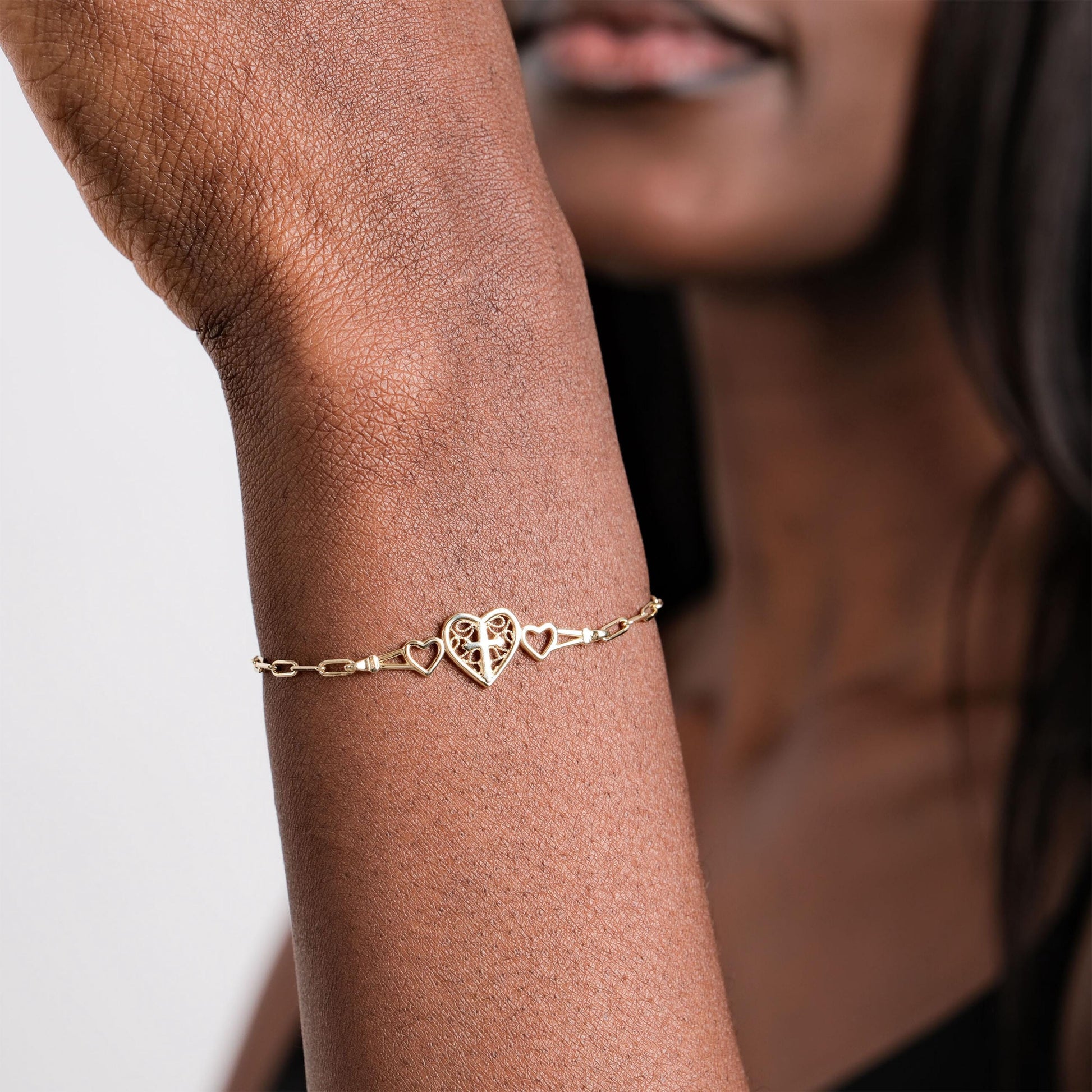 A close-up of a woman's wrist adorned with a 14K Solid Gold Paperclip Bracelet featuring a delicate heart design.