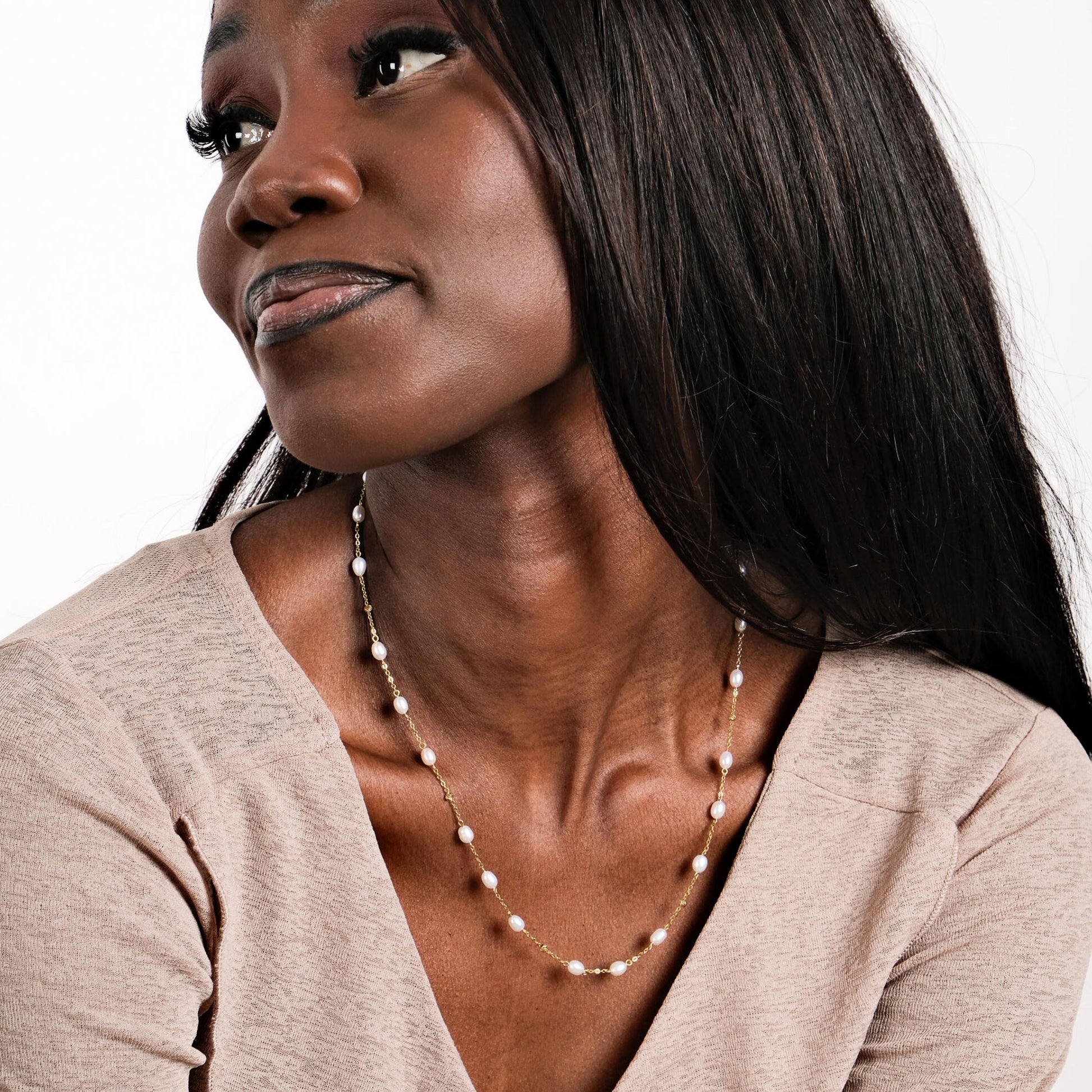 A model tilts her head slightly, showing off the luminous beauty of the 14K Solid Gold Freshwater Pearl Necklace in a naturally radiant pose.