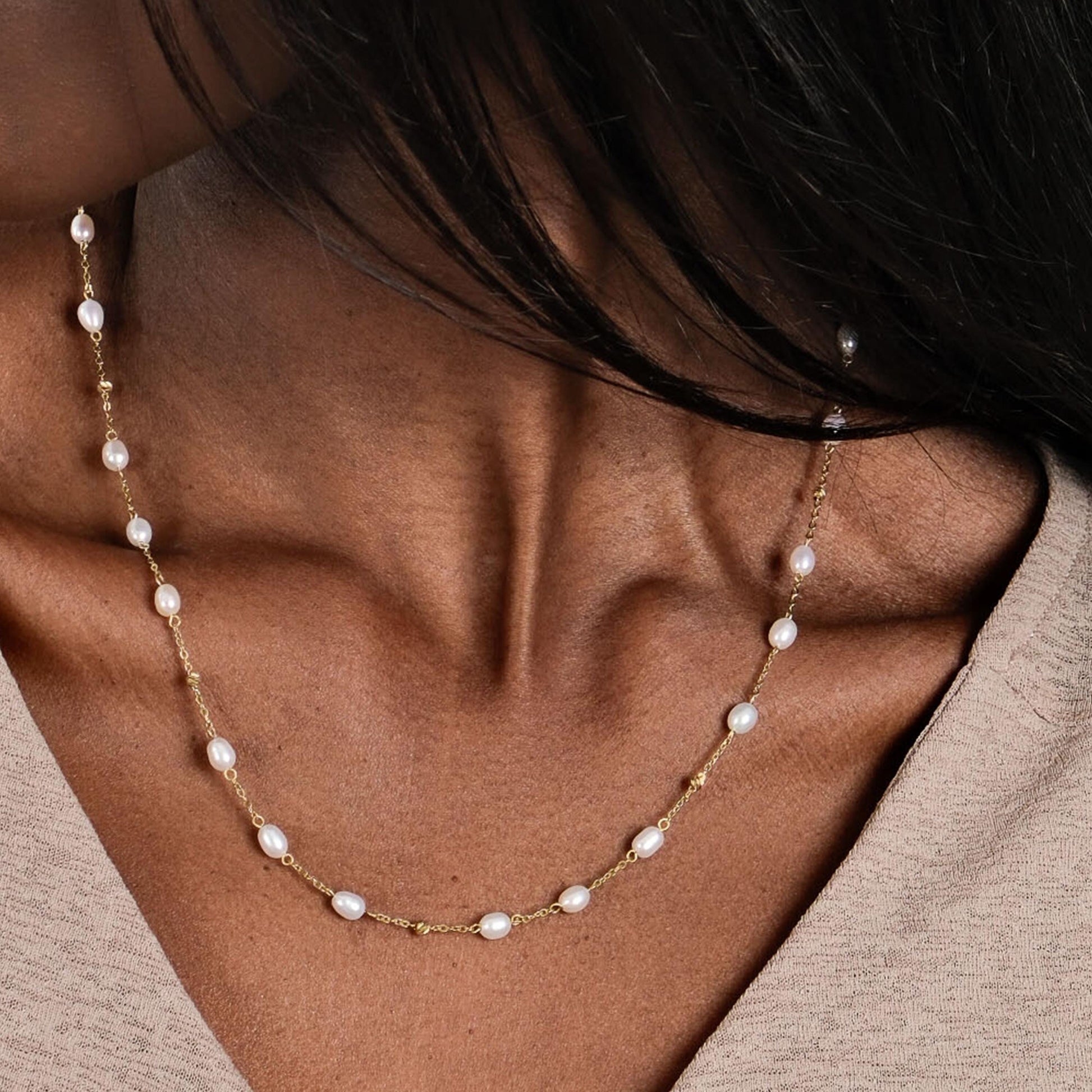 A close-up of a woman's neck showcases the elegance of the 14K Solid Gold Freshwater Pearl Necklace, featuring delicately spaced pearls on a fine gold chain.