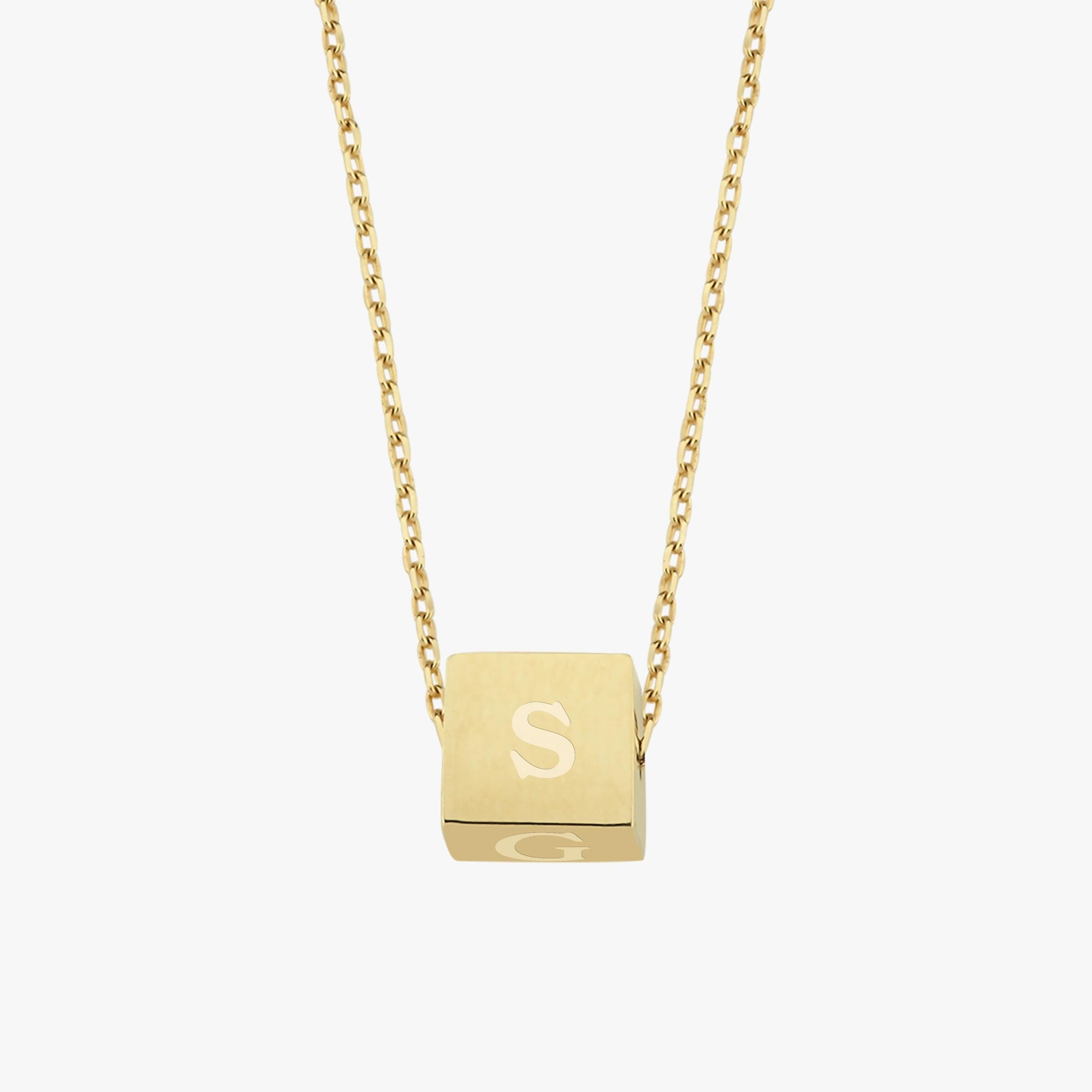 A floating cube pendant on a fine gold chain, engraved with the letter "S", photographed against a white background.