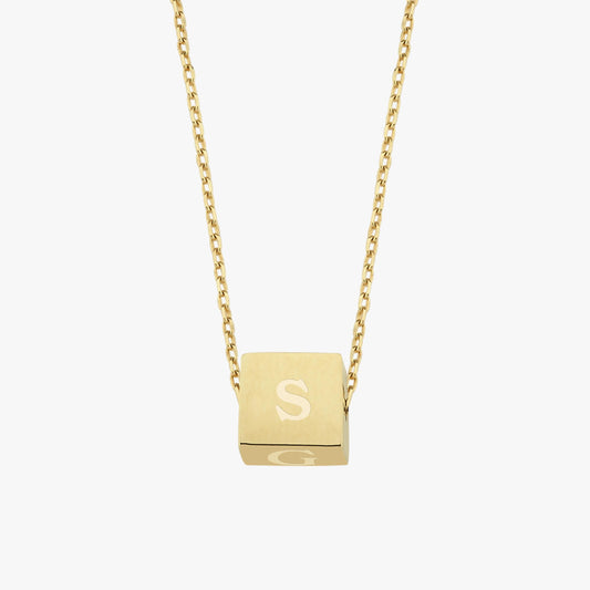 A floating cube pendant on a fine gold chain, engraved with the letter "S", photographed against a white background.