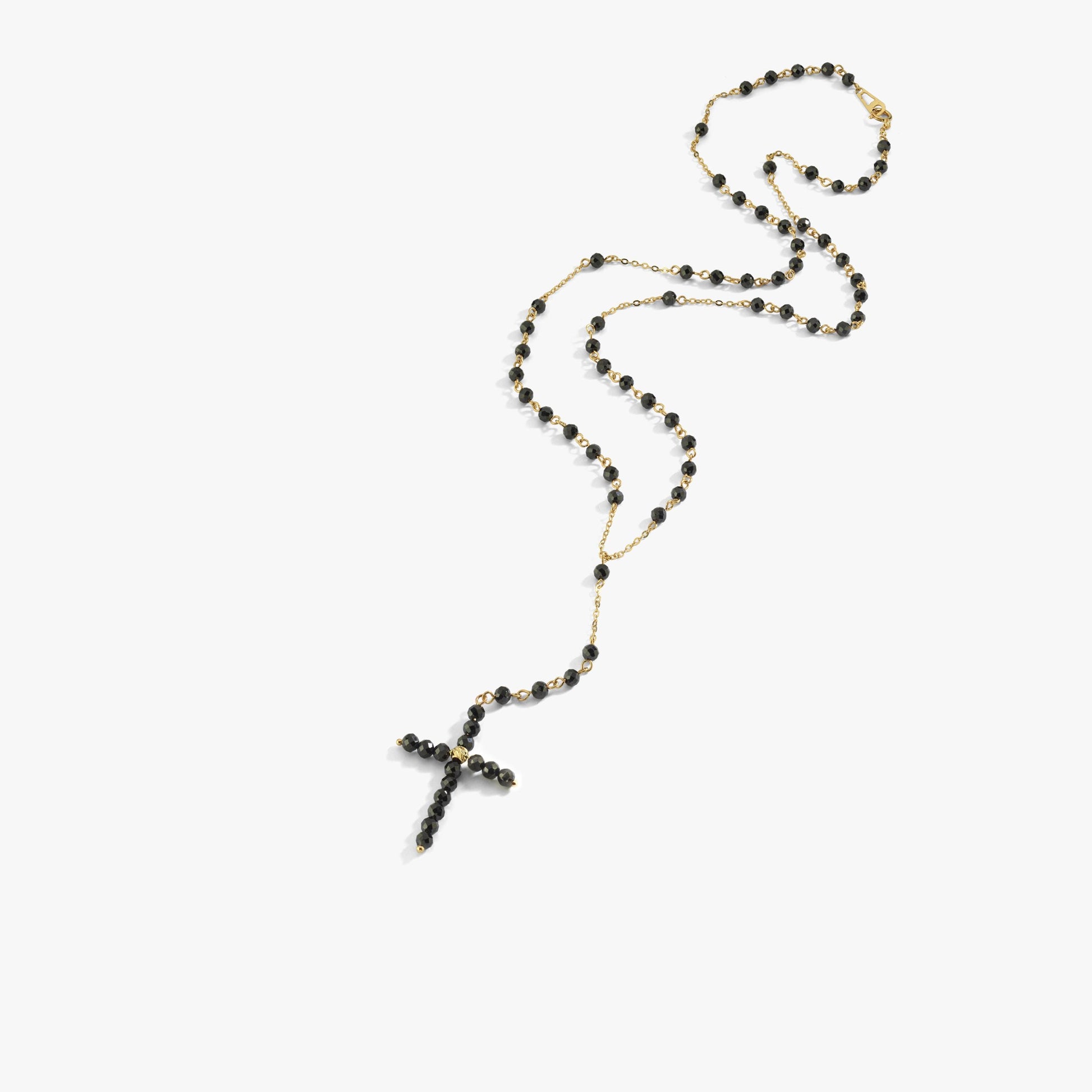 A close-up of a gold rosary necklace with faceted black onyx beads and a sleek Y-chain design.