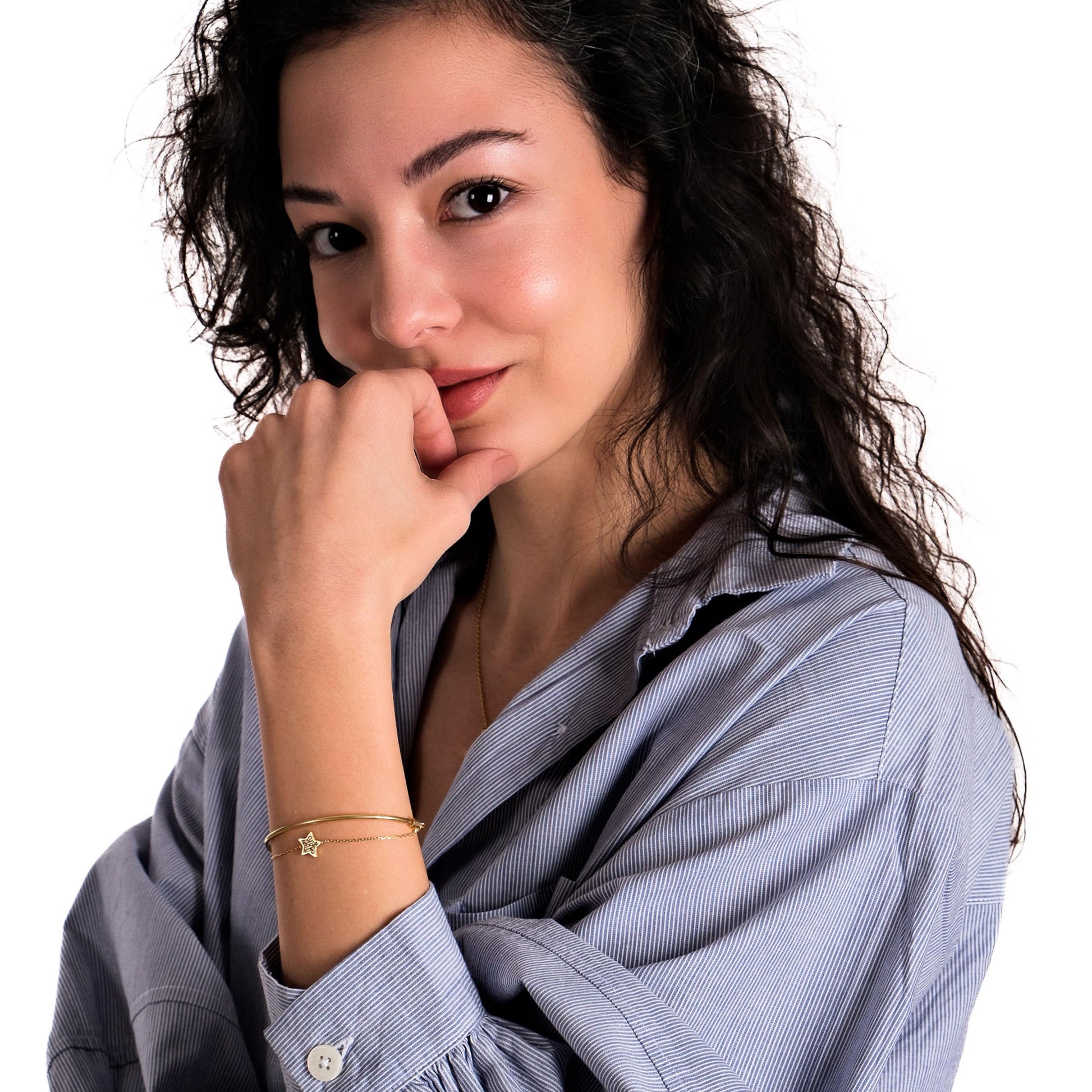 A woman poses with her hand near her face, wearing a stylish 18K gold vermeil sliding adjustable bracelet on her wrist.