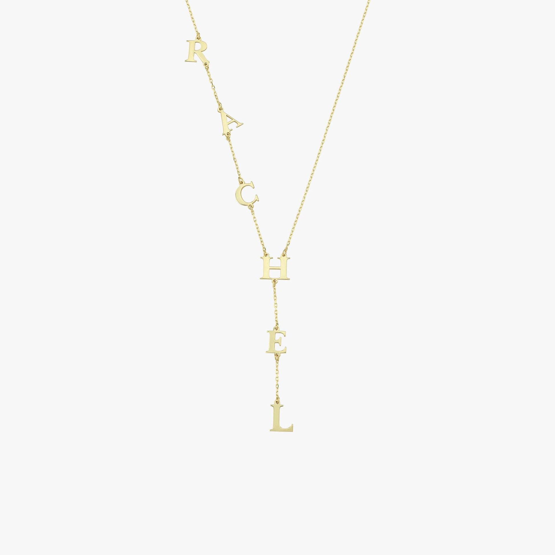 Minimalist product shot of a 14K solid gold lariat necklace with bold, spaced-out “RACHEL” letters.