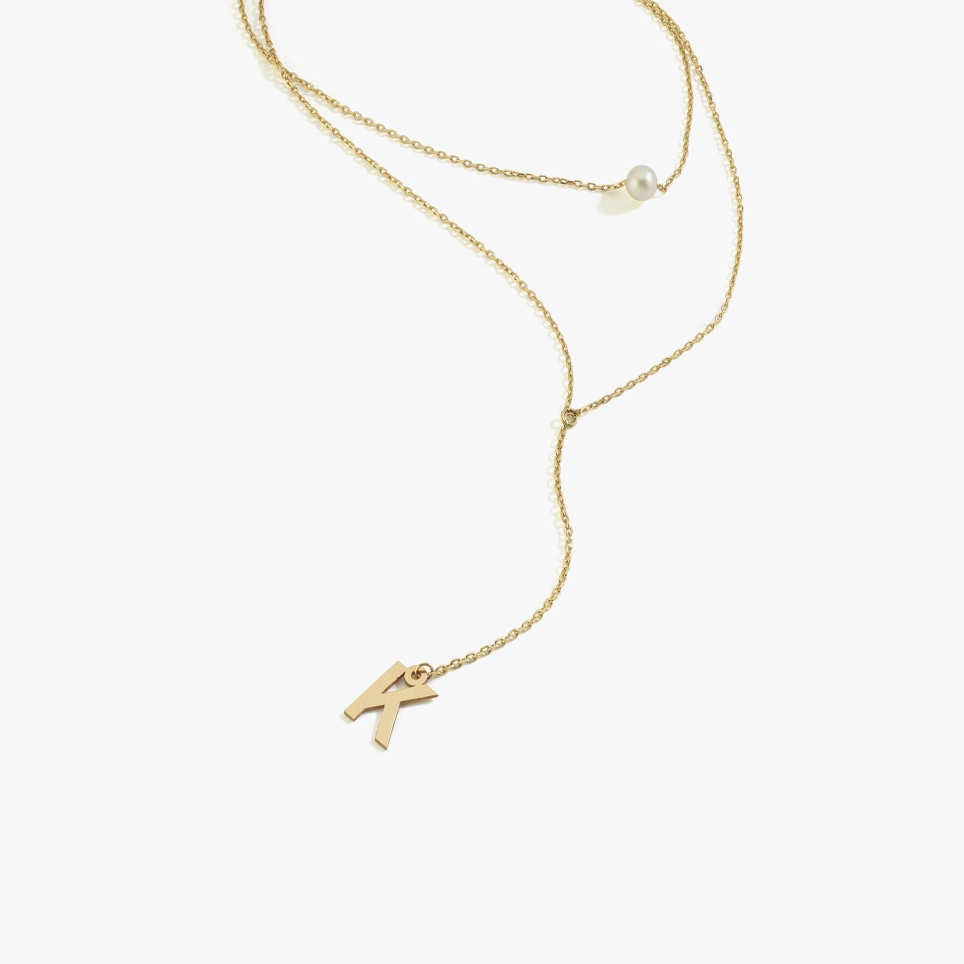 Minimalist 14K solid gold pearl lariat necklace displayed on a white background, showcasing its fine chain with a pearl and an initial charm.