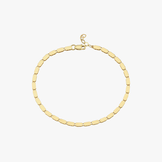 A side profile of a model wearing a 14K gold mirror chain bracelet, reflecting subtle golden hues.
