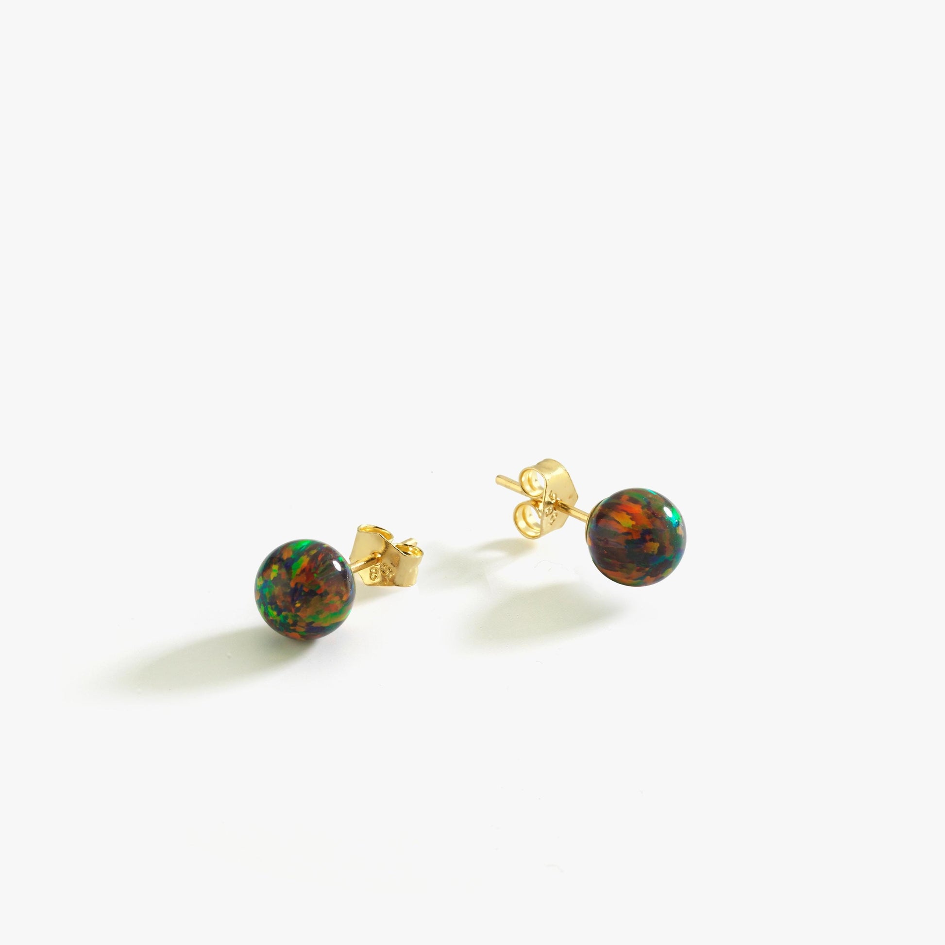A pair of 14K gold fire opal stud earrings displayed against a white background, showcasing their deep hues.
