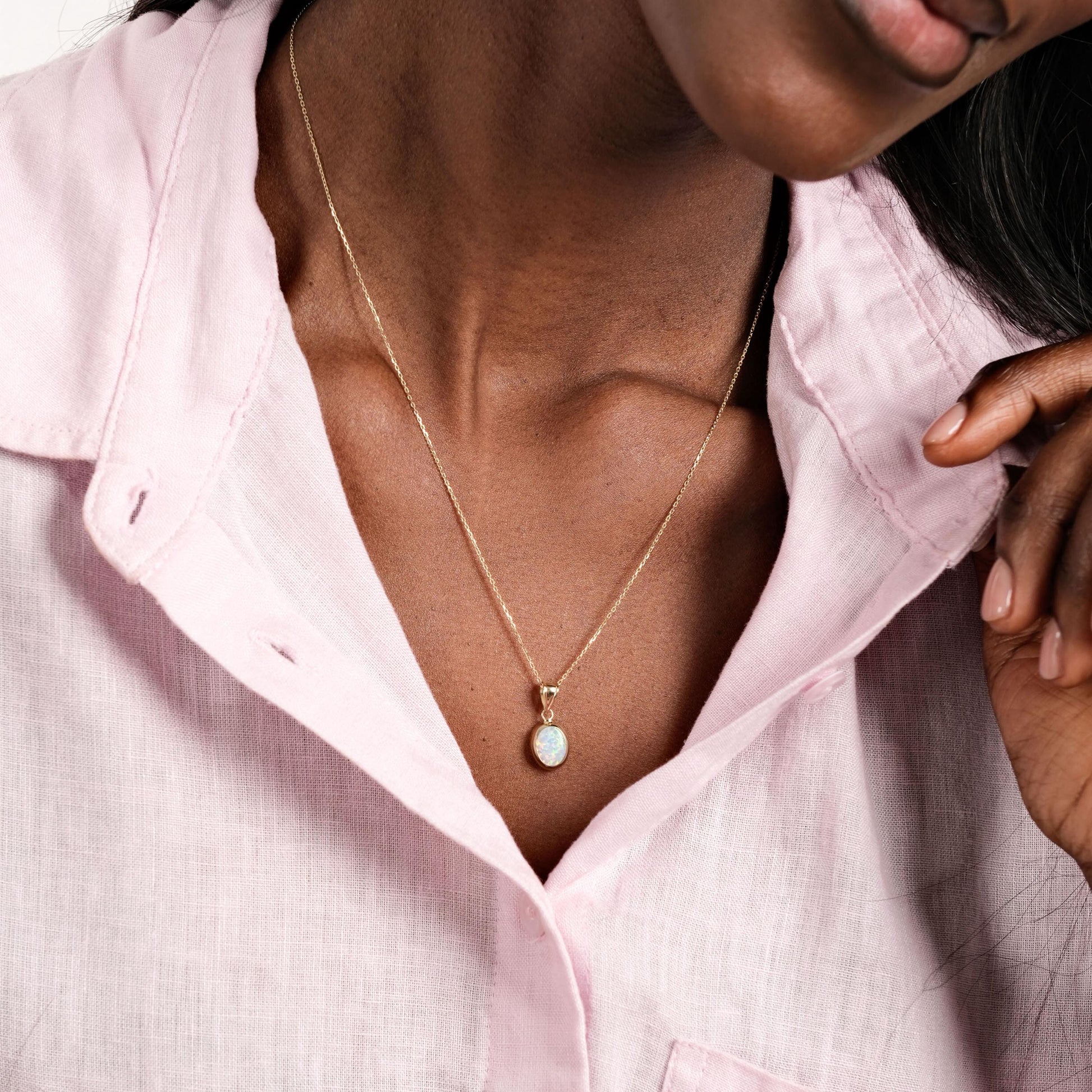 The model pairs a soft pink blouse with the 14K Solid Gold White Opal Necklace, enhancing the opal’s delicate glow.