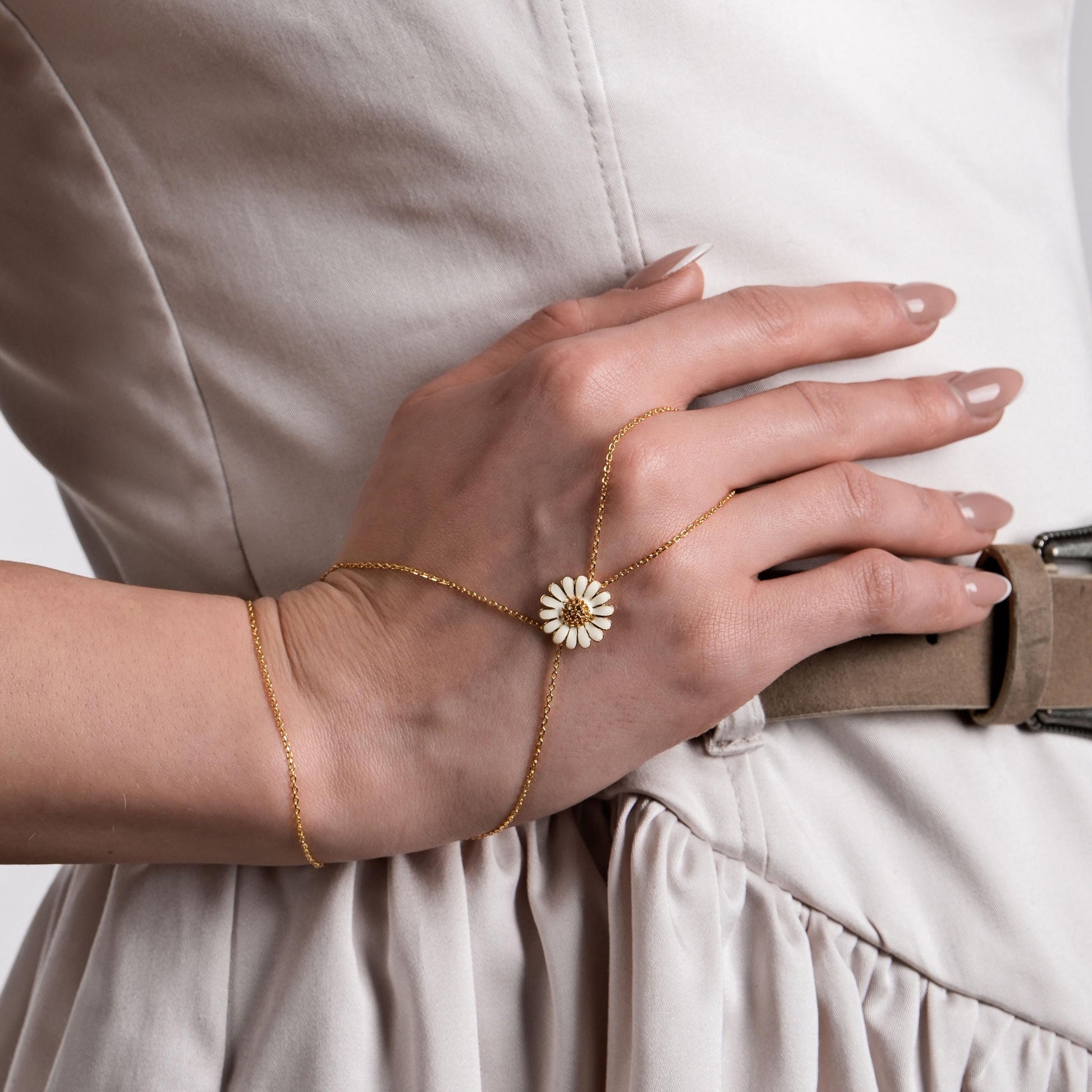 The hand chain bracelet complements a neutral-toned outfit, enhancing the model’s sophisticated look.