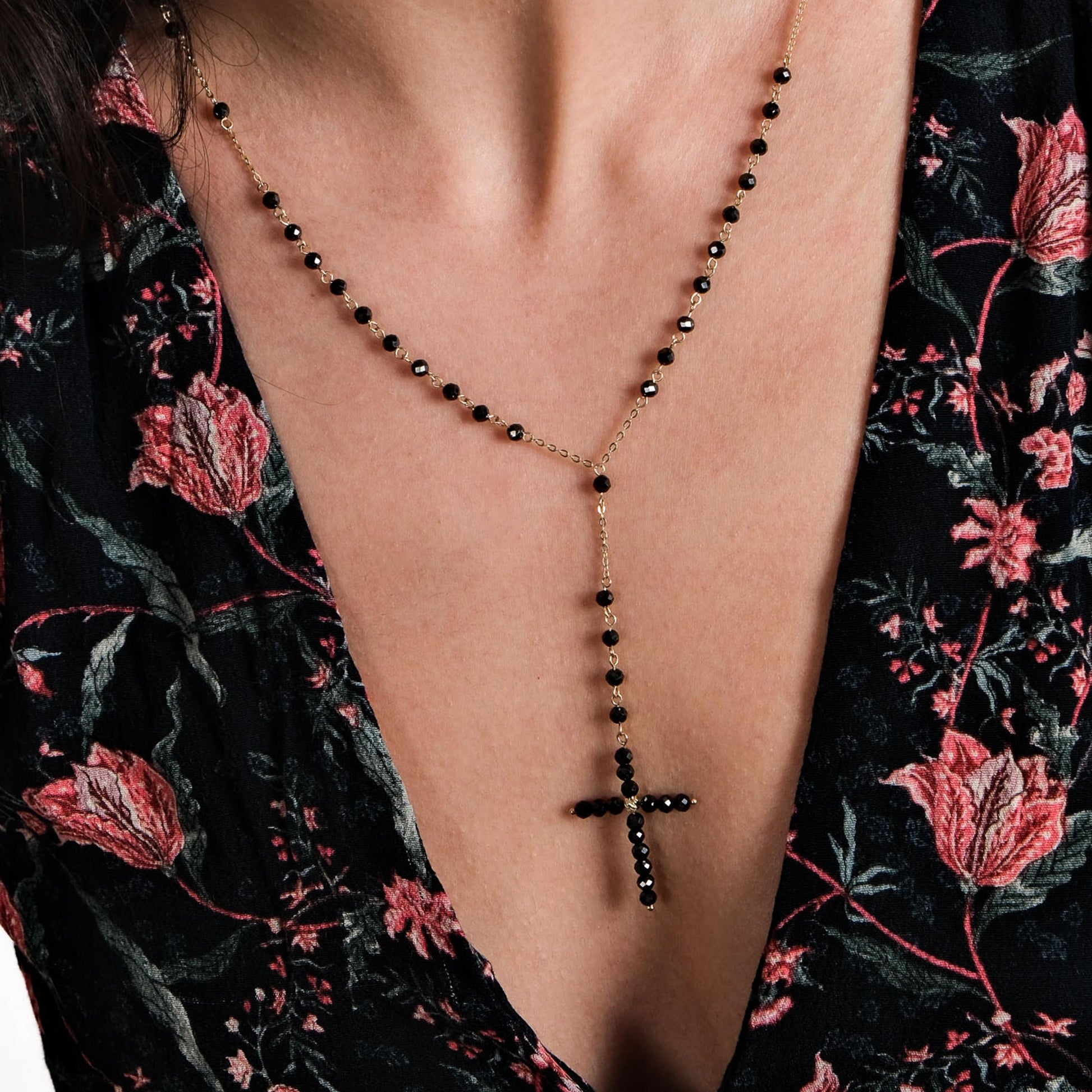 A 14K solid gold rosary necklace featuring black onyx beads and a delicate cross pendant.