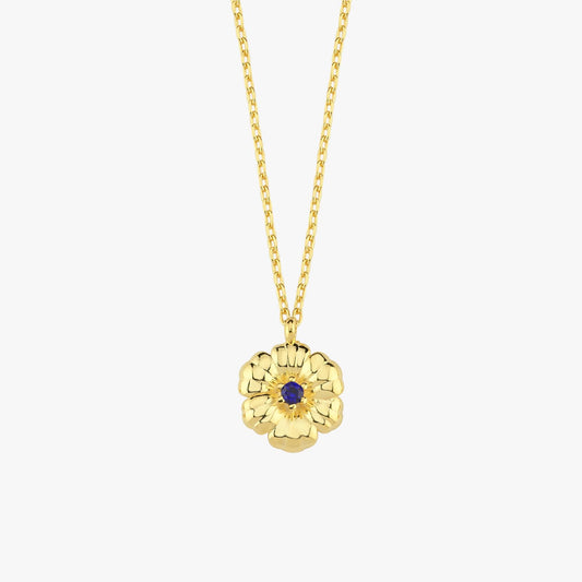 Studio image of an 18K gold vermeil flower necklace with textured petals and a deep blue sapphire at the center.