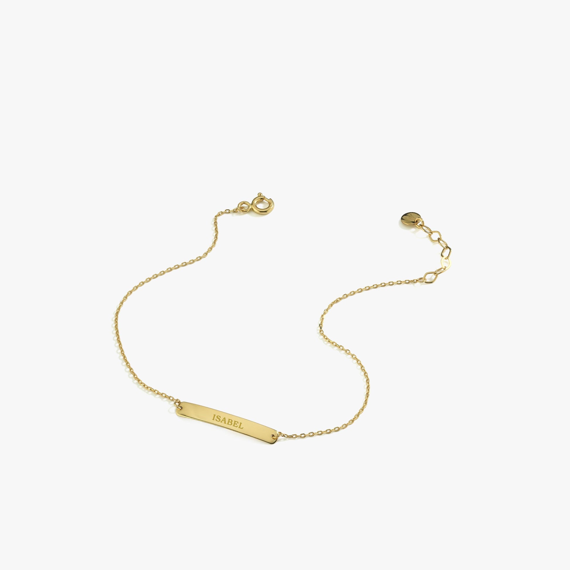 Minimalistic flat lay of a 14K solid gold custom name bracelet with "ISABEL" engraved on a rectangular plate and a fine chain, unclasped.