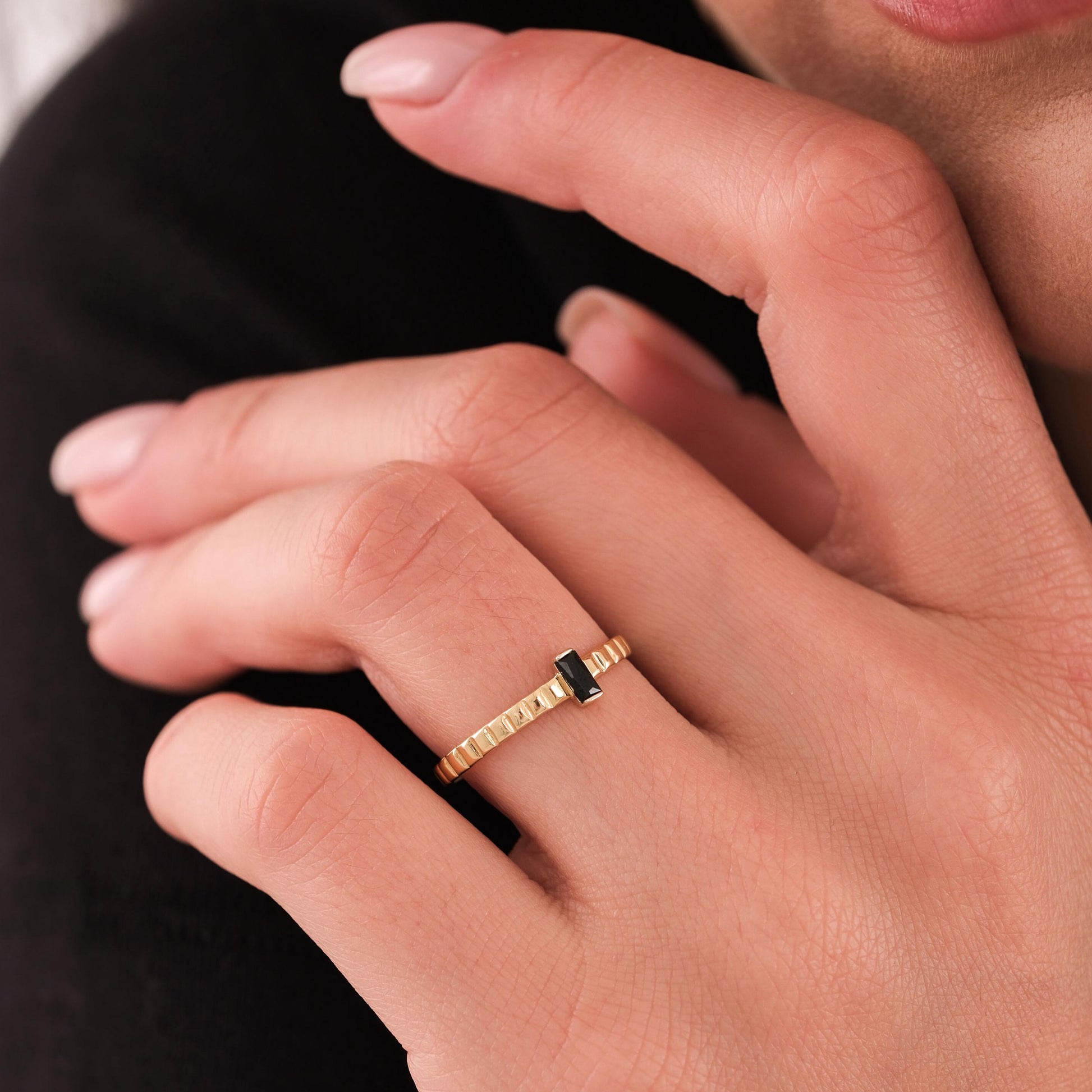 Detailed view of a 14K solid gold black onyx ring worn on the index finger, featuring a minimalist rectangular design.
