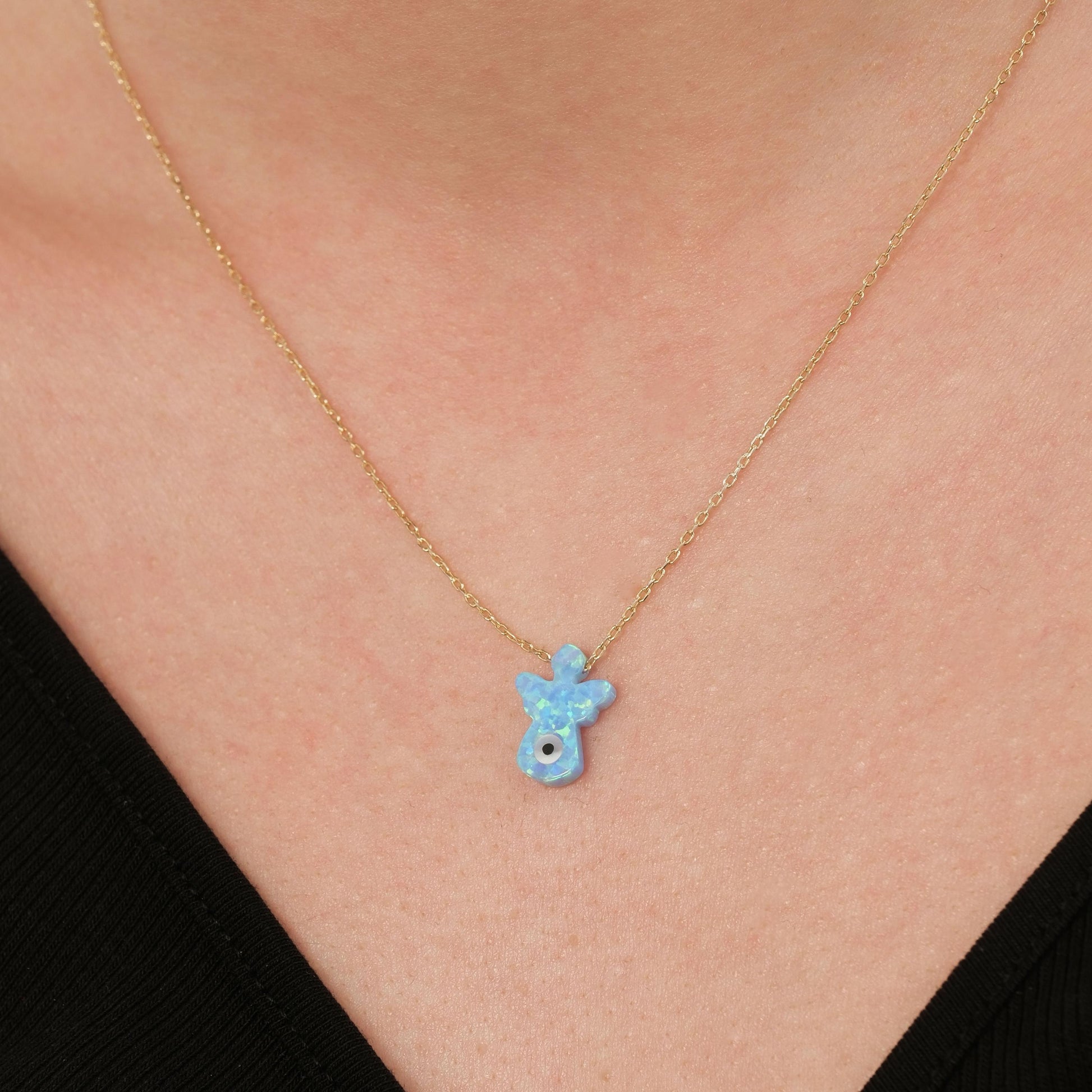 Delicate 14K solid gold opal angel necklace resting on the collarbone, showing the light-catching opal charm.