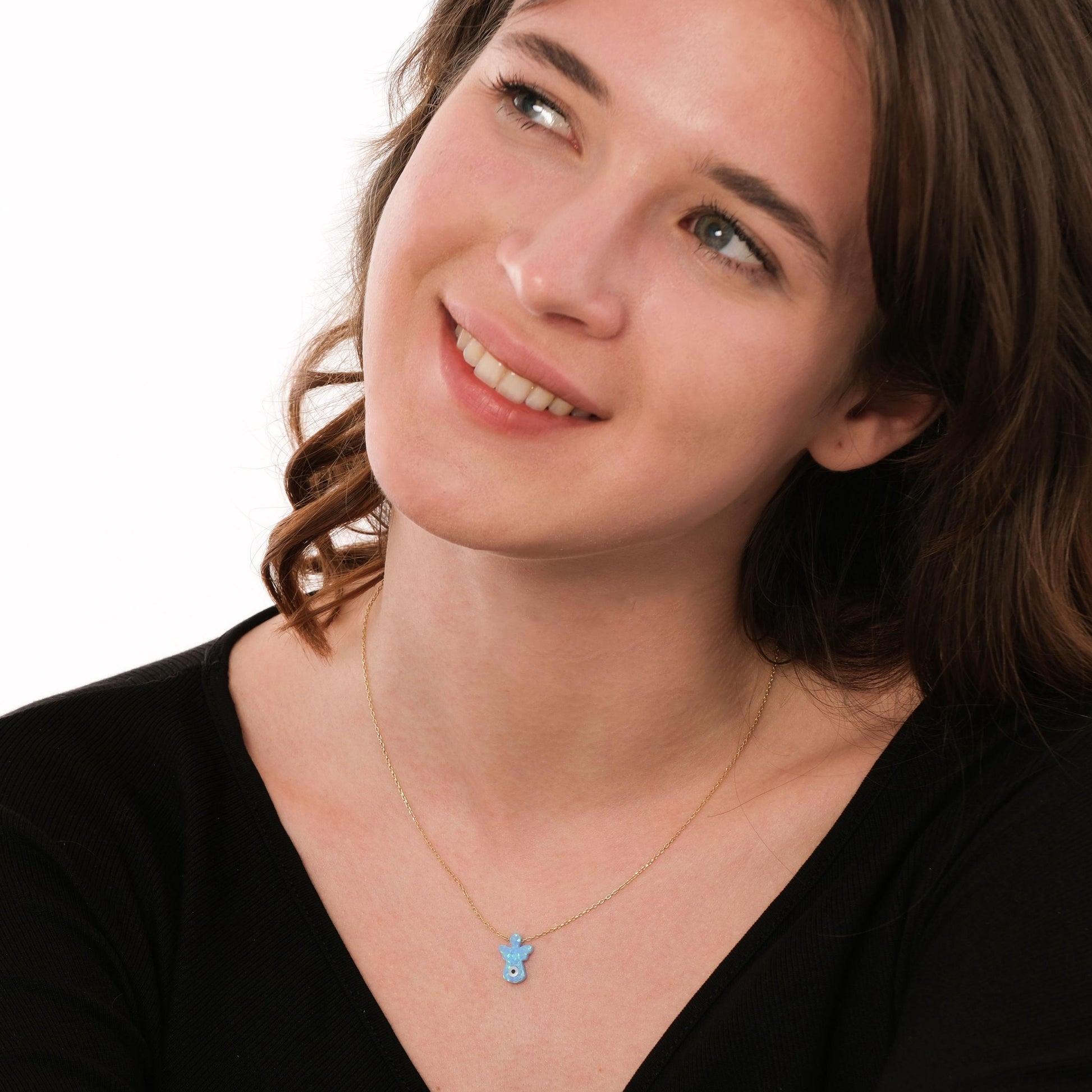 Smiling model wears a 14K solid gold opal angel necklace with a luminous baby blue opal charm.
