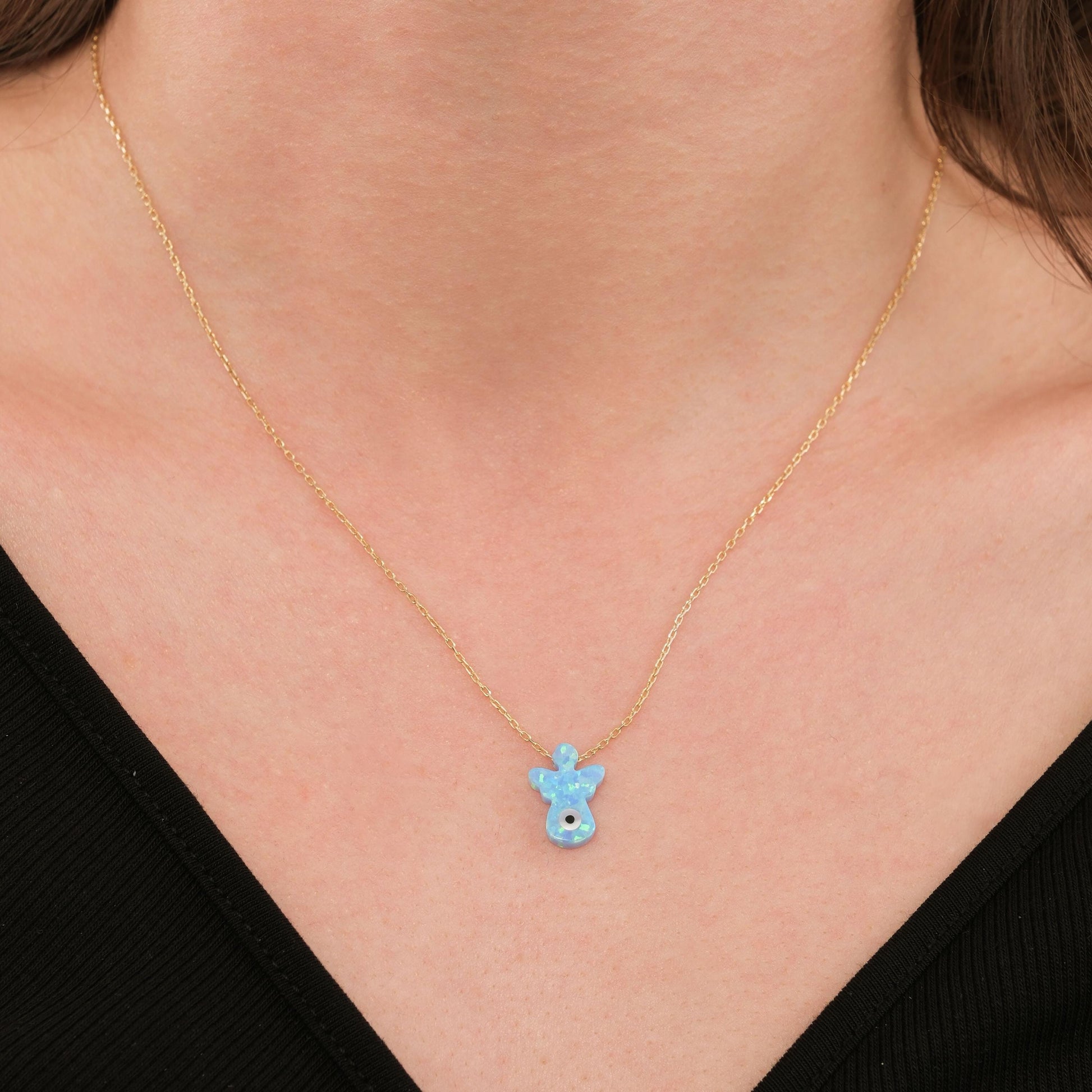 Close-up of a woman wearing a 14K solid gold opal angel necklace with a soft blue opal charm.