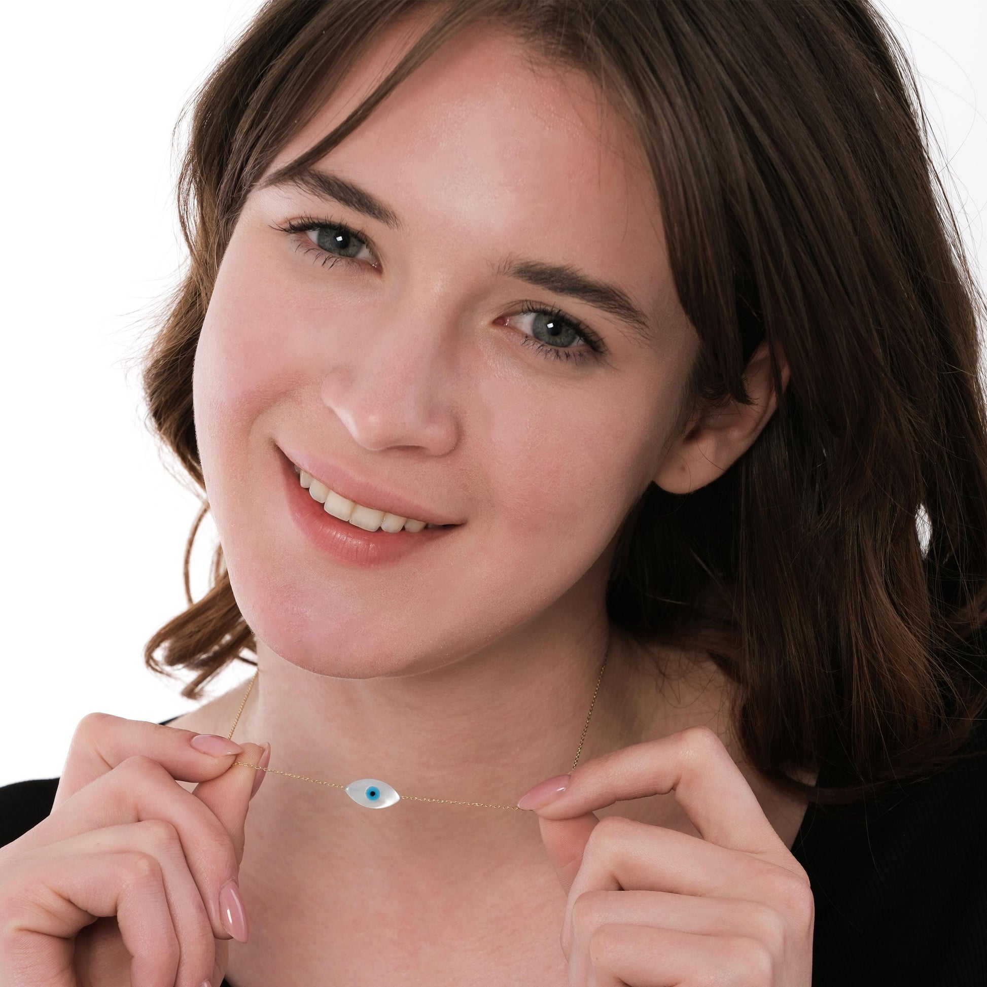 Smiling model holds and displays her 14K solid gold white opal necklace, showing the fine chain and centered charm.