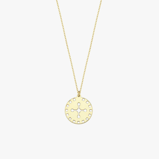 Detailed shot of the solar cross pendant on a 14K solid gold necklace, photographed on a neutral beige background.