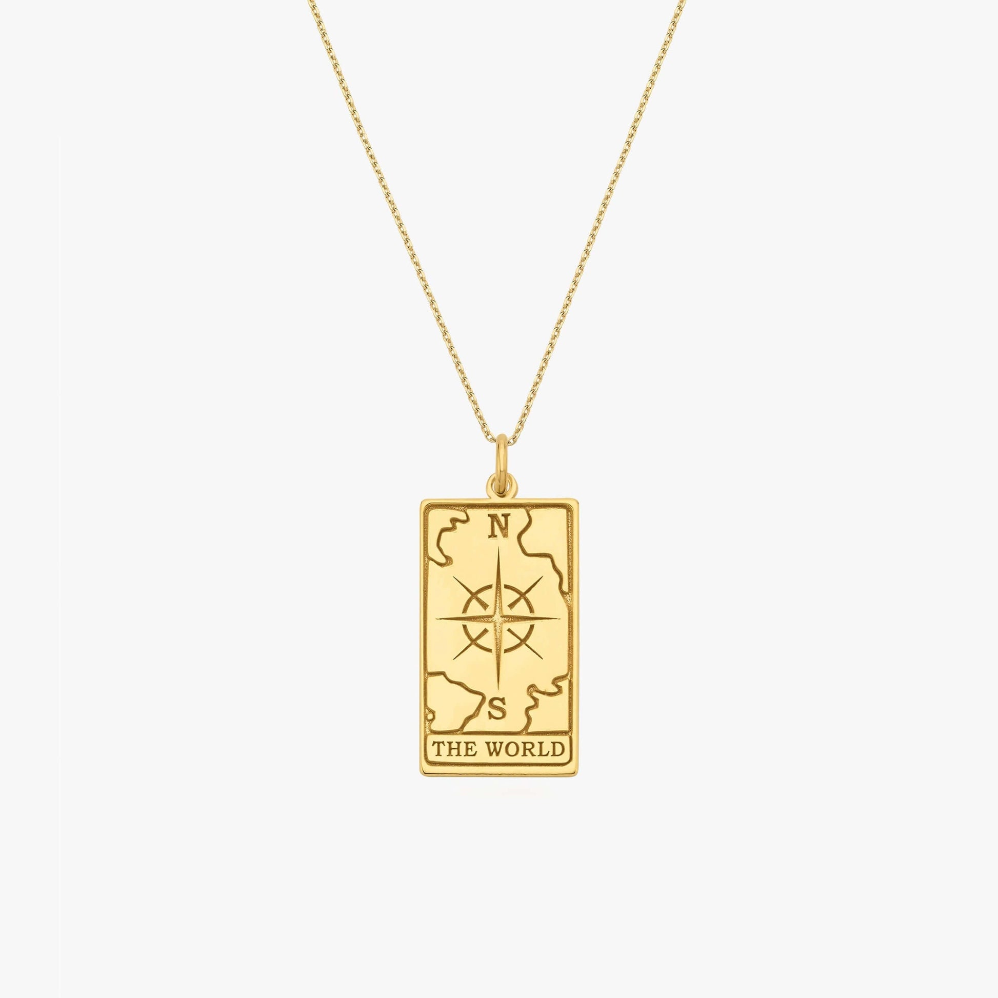 Gold necklace with rectangular pendant featuring compass design and "The World" engraving, symbolizing global journey.