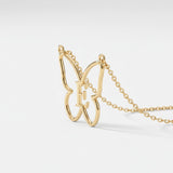 Gold butterfly initial necklace: an open outline butterfly with a serif initial E at its centre on a cable chain