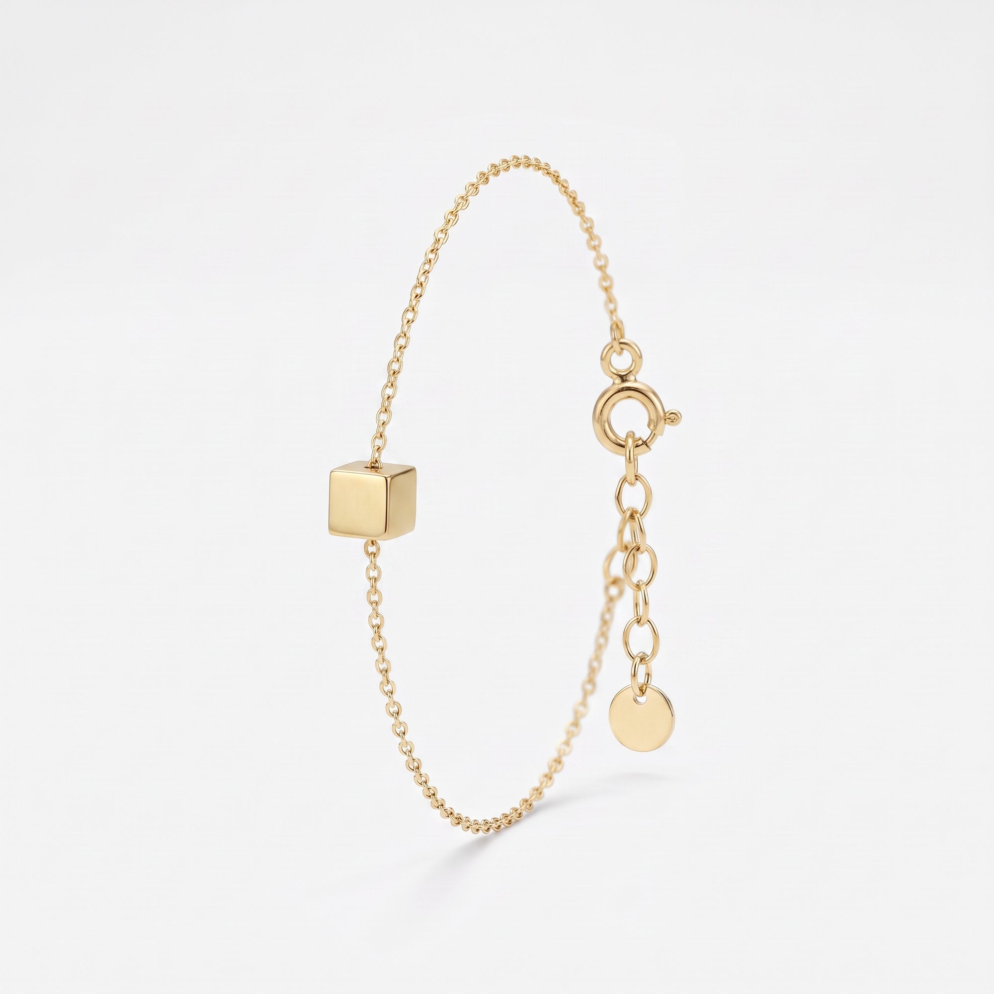 Gold initial bracelet with a polished cube charm for a custom engraved letter, on a dainty cable chain with extender
