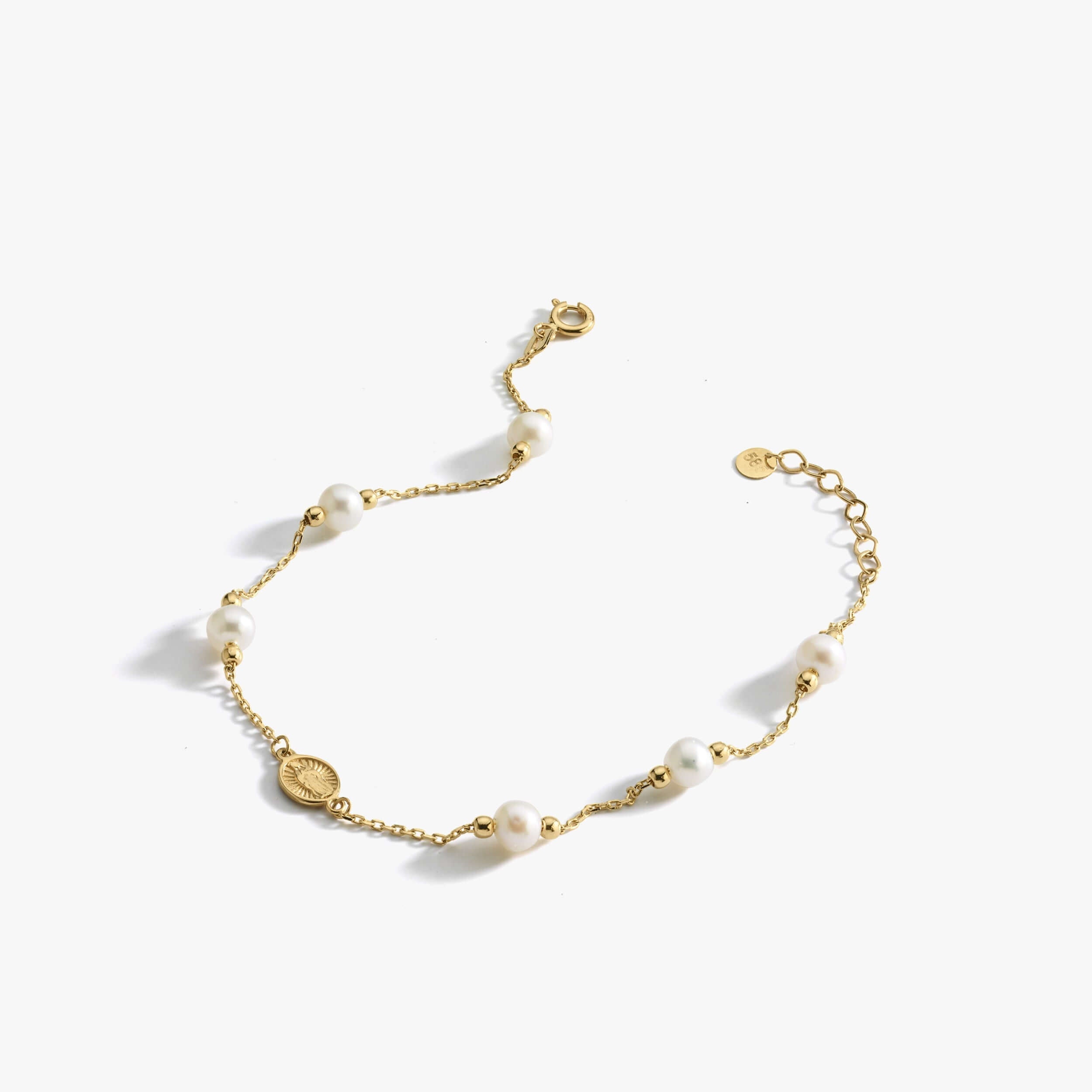 The Mionza Miraculous Medal Bracelet with Real Pearl is a delicate 14K solid gold chain bracelet adorned with white pearls and small gold beads. It features an adjustable clasp and a tiny coin charm near the closure. This elegant and minimalist design is perfect for various occasions.
