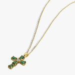 Gold chain with emerald cross pendant, white background, elegant jewelry design for fashion enthusiasts.