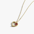 The Mionza Garnet Red Heart Necklace in 14K solid gold showcases a delicate heart-shaped pendant with a small, round garnet gemstone set within its design. The chain is thin and features a simple, adjustable design. This romantic gift necklace is elegantly displayed on a white background.