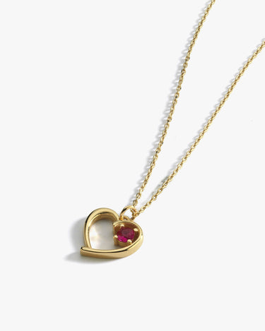 The Mionza Garnet Red Heart Necklace in 14K solid gold showcases a delicate heart-shaped pendant with a small, round garnet gemstone set within its design. The chain is thin and features a simple, adjustable design. This romantic gift necklace is elegantly displayed on a white background.