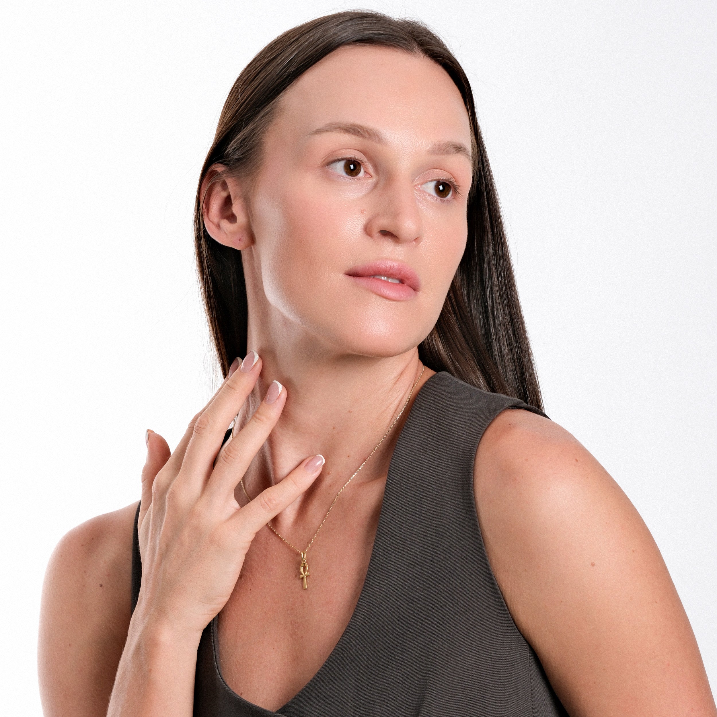 Woman wearing a gold necklace poses gracefully, showcasing elegant fashion style and minimalist jewelry.