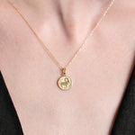 Gold pendant necklace with horse design on woman's neck, featuring delicate chain and elegant round charm.