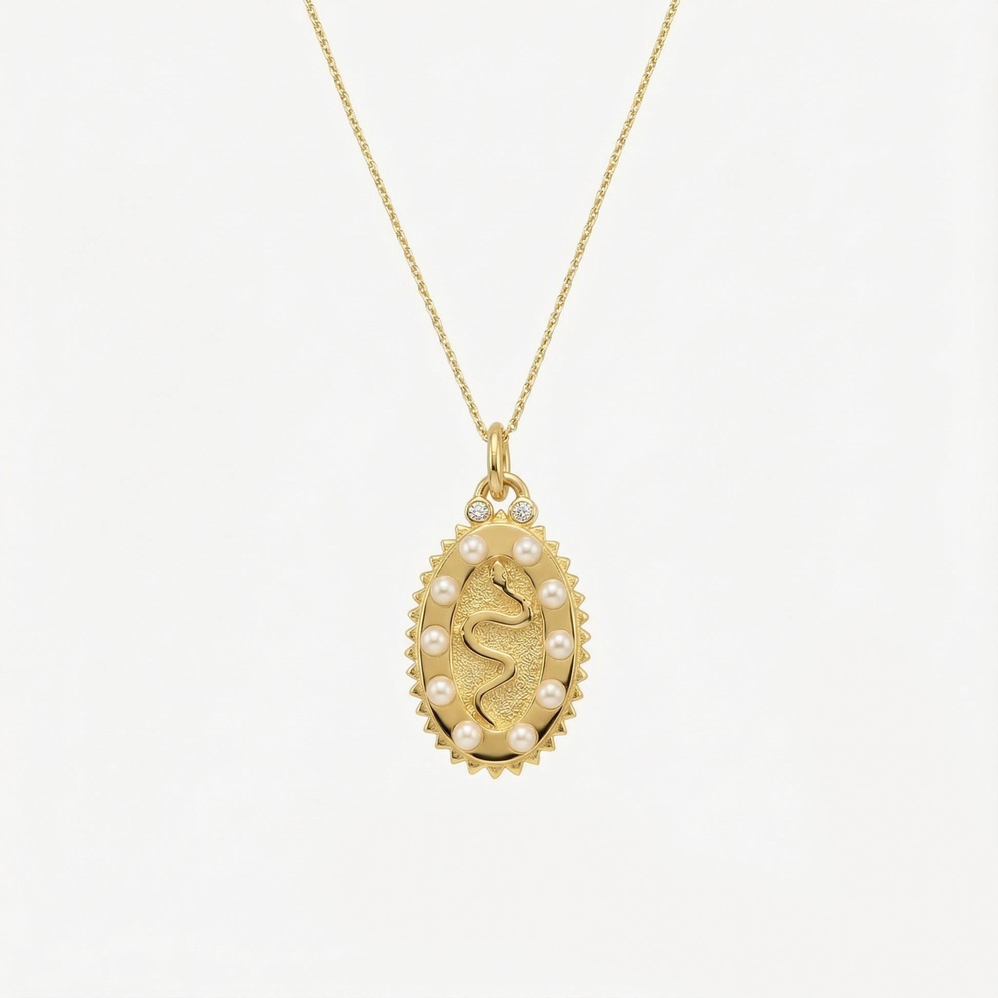 Gold necklace with a pendant featuring a face design on a white background