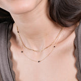 Woman wearing elegant layered gold chain necklaces with black beads, showcasing modern jewelry fashion.