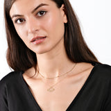 Woman wearing planet necklace, black top, minimal makeup, close-up portrait, elegant style, white background.