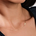 Close-up of a delicate gold cross necklace on a woman's neck, showcasing minimalist jewelry elegance.