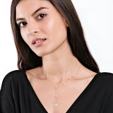 Woman wearing elegant gold heart necklace, black top, posing against white background, showcasing minimalist jewelry style.