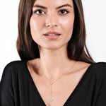 Woman wearing a black top and heart-shaped gold necklace, showcasing elegant jewelry style.