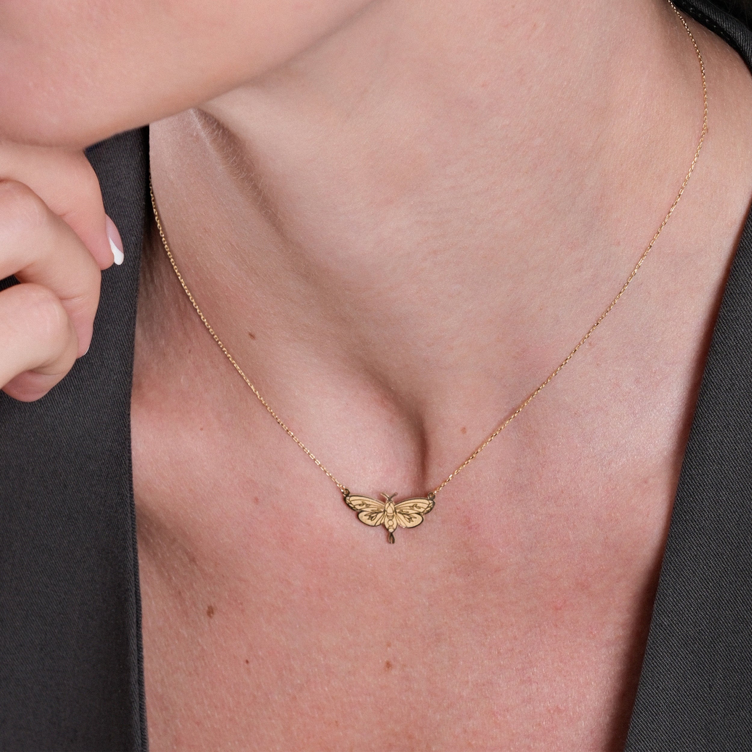 Elegant gold butterfly necklace on woman's neck, stylish jewelry fashion accessory close-up.