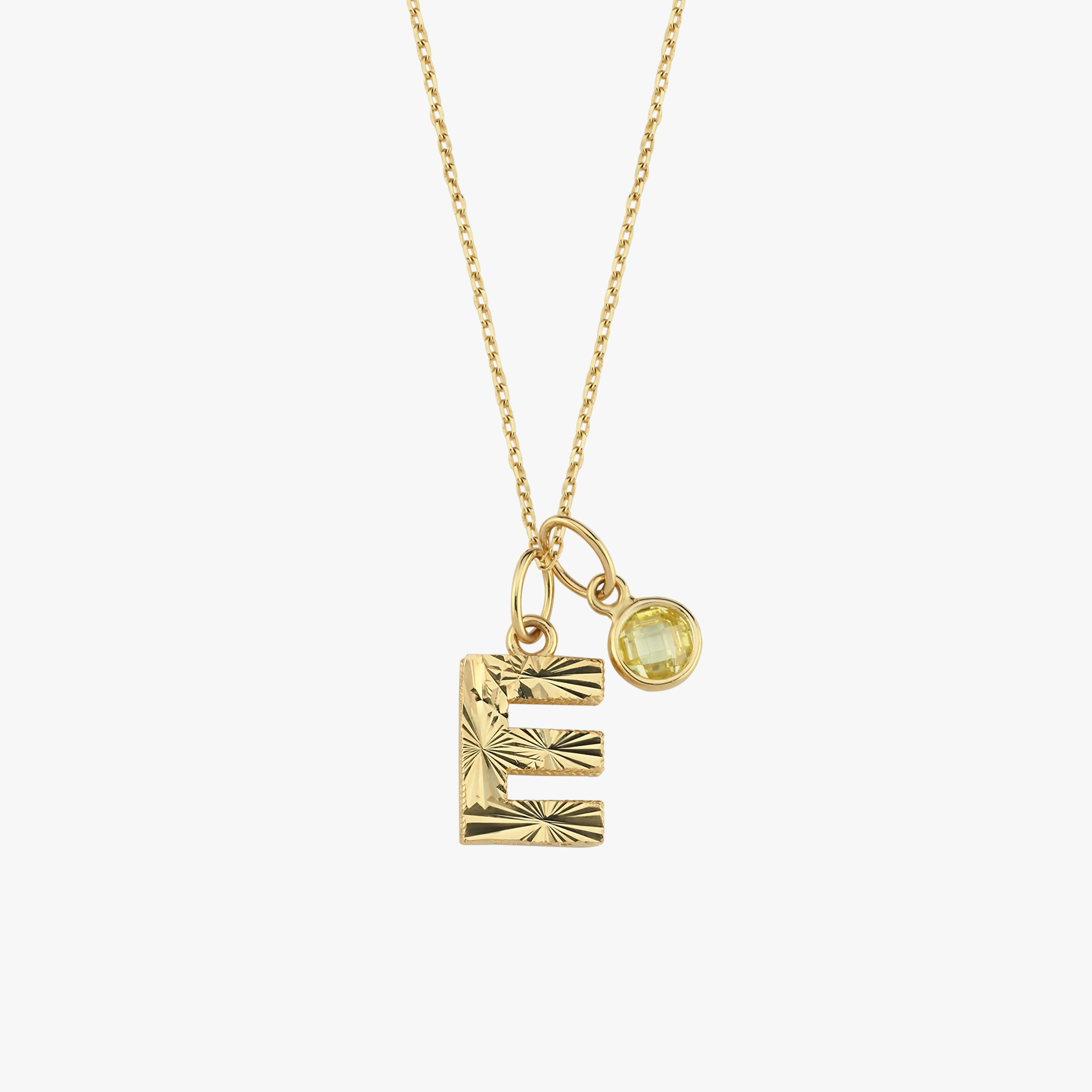 Gold necklace with engraved letter "E" pendant and yellow gemstone charm on delicate chain. Elegant jewelry accessory.